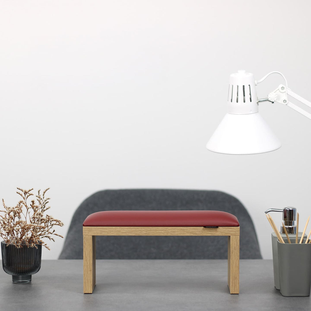 Podpórka do manicure SPENVI Classic czerwona z drewnianymi nogami ustawiona na biurku w salonie stylizacji paznokci. #kolor_bordo