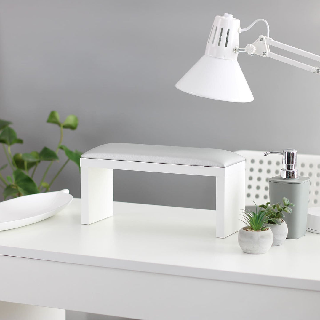 Podpórka do manicure SPENVI Classic w kolorze srebrnym na białych nogach ustawiona na biurku w salonie kosmetycznym pod lampą. #kolor_silver