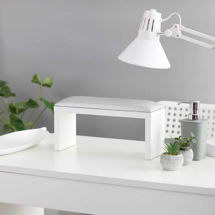 Podpórka do manicure SPENVI Classic w kolorze srebrnym na białych nogach ustawiona na biurku w salonie kosmetycznym pod lampą. #kolor_silver